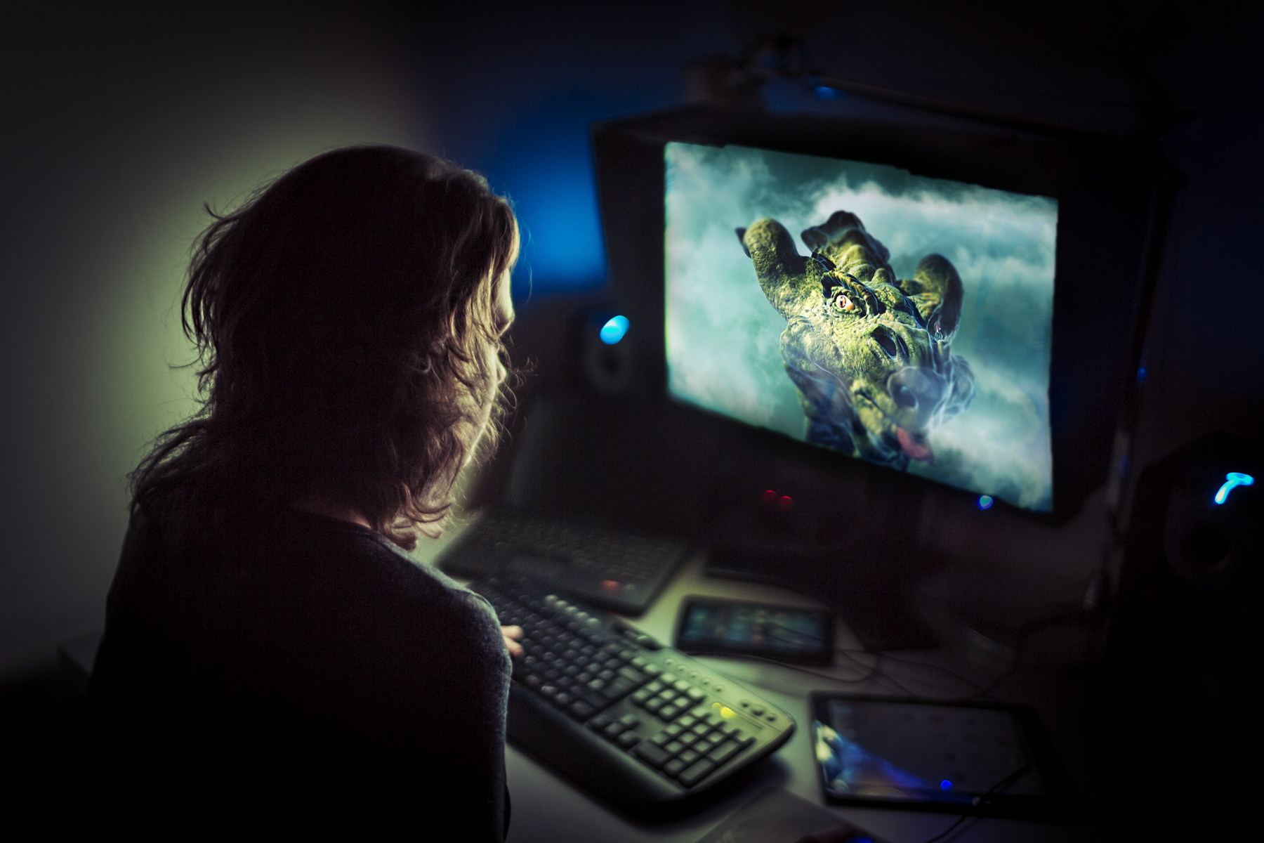 graphic artist working late at night. Dragon imagery is displayed on the monitor